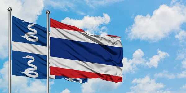 Martinica e bandeira da Tailândia agitando no vento contra o céu azul nublado branco juntos. Conceito de diplomacia, relações internacionais . — Fotografia de Stock