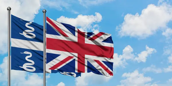 Martinique och Förenade kungariket sjunker vifta i vinden mot vit grumlig blå himmel tillsammans. Diplomatisk koncept, internationella relationer. — Stockfoto