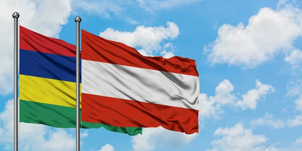 Bandera de Mauricio y Austria ondeando en el viento contra el cielo azul nublado blanco juntos. Concepto diplomático, relaciones internacionales . — Foto de Stock