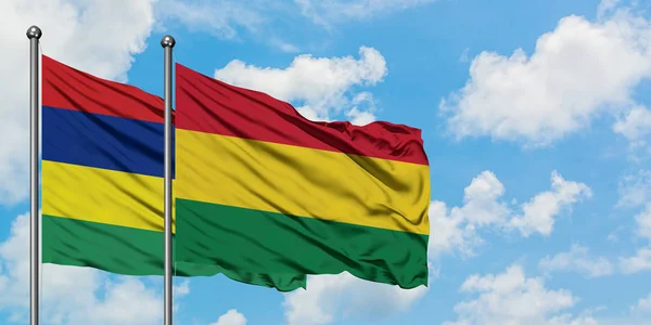 Bandera de Mauricio y Bolivia ondeando en el viento contra el cielo azul nublado blanco juntos. Concepto diplomático, relaciones internacionales . — Foto de Stock