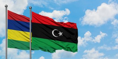 Mauritius ve Libya bayrağı birlikte beyaz bulutlu mavi gökyüzüne karşı rüzgarda sallayarak. Diplomasi kavramı, uluslararası ilişkiler.