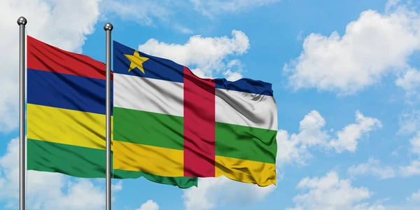 Mauricio y la República Centroafricana ondean en el viento contra el cielo azul nublado blanco juntos. Concepto diplomático, relaciones internacionales . — Foto de Stock