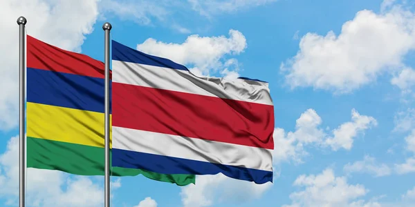 Mauritius e la bandiera del Costa Rica sventolano insieme nel vento contro il bianco cielo blu nuvoloso. Concetto di diplomazia, relazioni internazionali . — Foto Stock