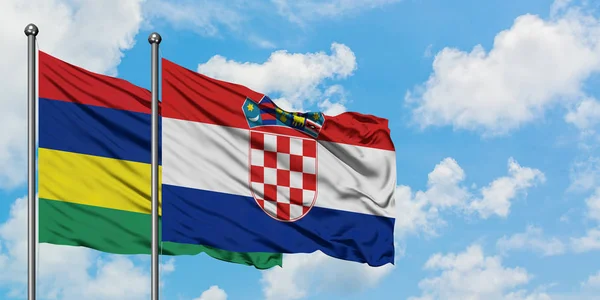 Bandera de Mauricio y Croacia ondeando en el viento contra el cielo azul nublado blanco juntos. Concepto diplomático, relaciones internacionales . — Foto de Stock