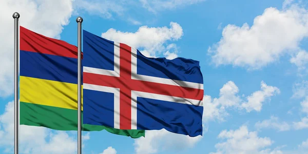 Bandera de Mauricio e Islandia ondeando en el viento contra el cielo azul nublado blanco juntos. Concepto diplomático, relaciones internacionales . — Foto de Stock