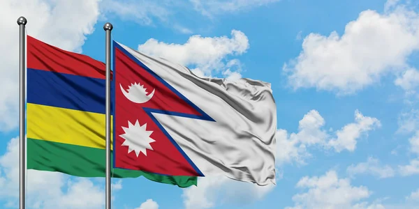 Bandera de Mauricio y Nepal ondeando en el viento contra el cielo azul nublado blanco juntos. Concepto diplomático, relaciones internacionales . — Foto de Stock