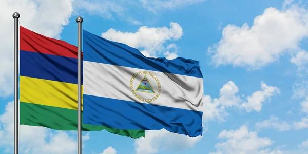 Bandera de Mauricio y Nicaragua ondeando en el viento contra el cielo azul nublado blanco juntos. Concepto diplomático, relaciones internacionales . — Foto de Stock
