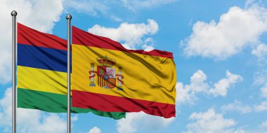 Mauritius ve İspanya bayrağı birlikte beyaz bulutlu mavi gökyüzüne karşı rüzgarda sallayarak. Diplomasi kavramı, uluslararası ilişkiler.