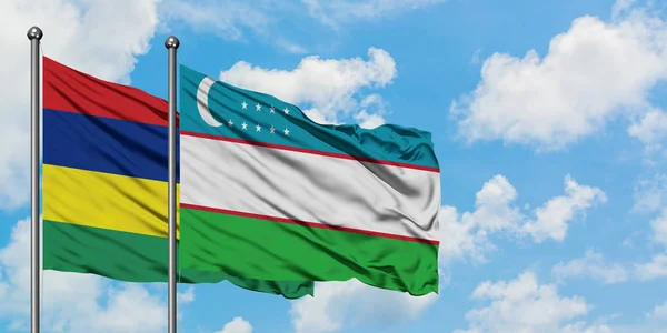 Bandera de Mauricio y Uzbekistán ondeando en el viento contra el cielo azul nublado blanco juntos. Concepto diplomático, relaciones internacionales . — Foto de Stock