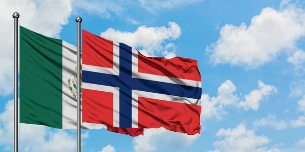 Bandera de México y Bouvet Islands ondeando en el viento contra el cielo azul nublado blanco juntos. Concepto diplomático, relaciones internacionales . — Foto de Stock