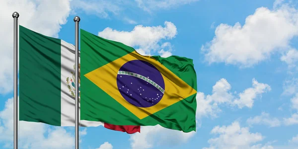 Bandera de México y Brasil ondeando en el viento contra el cielo azul nublado blanco juntos. Concepto diplomático, relaciones internacionales . — Foto de Stock