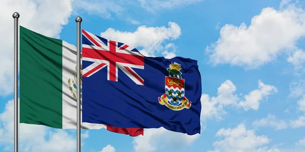 Bandera de México y las Islas Caimán ondeando en el viento contra el cielo azul nublado blanco juntos. Concepto diplomático, relaciones internacionales . — Foto de Stock