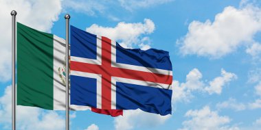 Meksika ve İzlanda bayrağı birlikte beyaz bulutlu mavi gökyüzüne karşı rüzgarda sallayarak. Diplomasi kavramı, uluslararası ilişkiler.