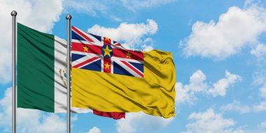 Meksika ve Niue bayrağı birlikte beyaz bulutlu mavi gökyüzüne karşı rüzgarda sallayarak. Diplomasi kavramı, uluslararası ilişkiler.