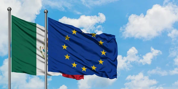 Bandera de México y la Unión Europea ondeando en el viento contra el cielo azul nublado blanco juntos. Concepto diplomático, relaciones internacionales . —  Fotos de Stock