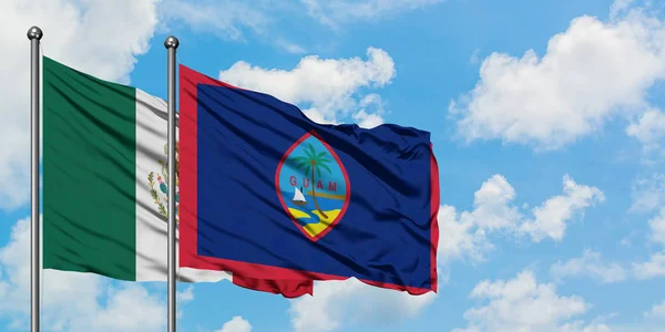 Bandera de México y Guam ondeando en el viento contra el cielo azul nublado blanco juntos. Concepto diplomático, relaciones internacionales . — Foto de Stock