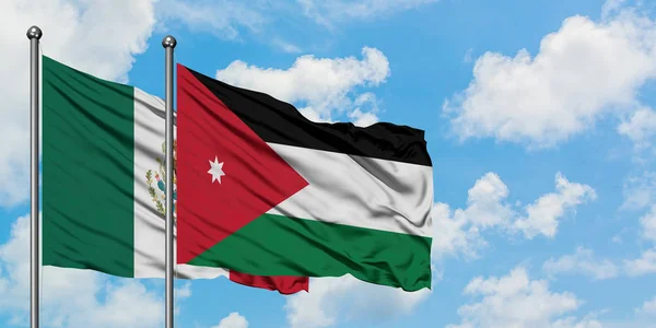 Bandera de México y Jordania ondeando en el viento contra el cielo azul nublado blanco juntos. Concepto diplomático, relaciones internacionales . — Foto de Stock