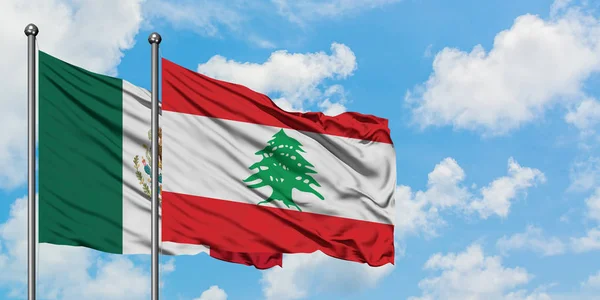 Bandera de México y Líbano ondeando en el viento contra el cielo azul nublado blanco juntos. Concepto diplomático, relaciones internacionales . — Foto de Stock