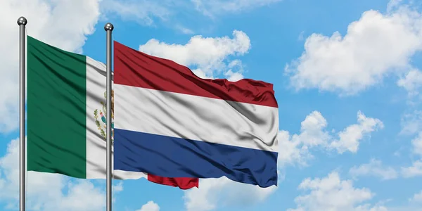 México e Holanda acenando com o vento contra o céu azul nublado branco juntos. Conceito de diplomacia, relações internacionais . — Fotografia de Stock