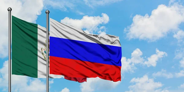 Bandera de México y Rusia ondeando en el viento contra el cielo azul nublado blanco juntos. Concepto diplomático, relaciones internacionales . —  Fotos de Stock