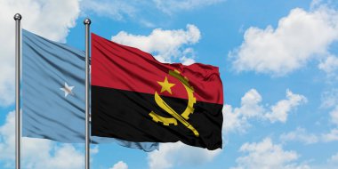 Mikronezya ve Angola bayrağı birlikte beyaz bulutlu mavi gökyüzüne karşı rüzgarda sallayarak. Diplomasi kavramı, uluslararası ilişkiler.