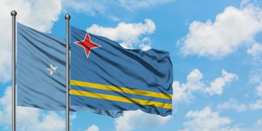 Mikronezya ve Aruba bayrağı birlikte beyaz bulutlu mavi gökyüzüne karşı rüzgarda sallayarak. Diplomasi kavramı, uluslararası ilişkiler.