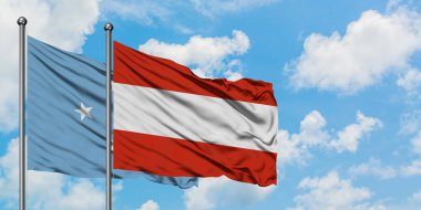 Mikronezya ve Avusturya bayrağı birlikte beyaz bulutlu mavi gökyüzüne karşı rüzgarda sallayarak. Diplomasi kavramı, uluslararası ilişkiler.