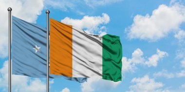 Mikronezya ve Fildişi Sahili bayrağı birlikte beyaz bulutlu mavi gökyüzüne karşı rüzgarda sallayarak. Diplomasi kavramı, uluslararası ilişkiler.