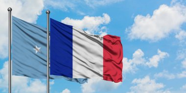 Mikronezya ve Fransa bayrağı birlikte beyaz bulutlu mavi gökyüzüne karşı rüzgarda sallayarak. Diplomasi kavramı, uluslararası ilişkiler.