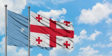 Mikronezya ve Gürcistan bayrağı birlikte beyaz bulutlu mavi gökyüzüne karşı rüzgarda sallayarak. Diplomasi kavramı, uluslararası ilişkiler.