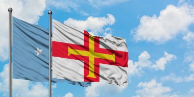 Mikronezya ve Guernsey bayrağı birlikte beyaz bulutlu mavi gökyüzüne karşı rüzgarda sallayarak. Diplomasi kavramı, uluslararası ilişkiler.