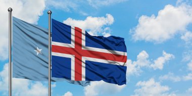 Mikronezya ve İzlanda bayrağı birlikte beyaz bulutlu mavi gökyüzüne karşı rüzgarda sallayarak. Diplomasi kavramı, uluslararası ilişkiler.