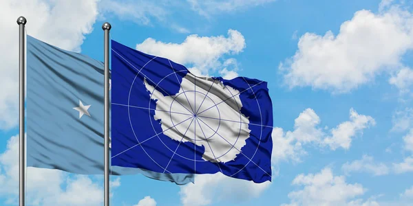 Σημαία της Μικρονησίας και της Ανταρκτικής που κουνώντας τον άνεμο ενάντια στο λευκό συννεφιασμένο γαλάζιο του ουρανού μαζί. Φιλοσοφία της διπλωματίας, διεθνείς σχέσεις. — Φωτογραφία Αρχείου
