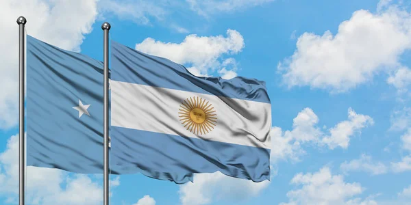 Micronesia y la bandera argentina ondeando en el viento contra el cielo azul nublado blanco juntas. Concepto diplomático, relaciones internacionales . — Foto de Stock