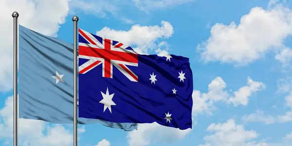 Mikronézia és Ausztrália zászló integetett a szél ellen, fehér felhős kék ég együtt. Diplomáciai koncepció, nemzetközi kapcsolatok. — Stock Fotó