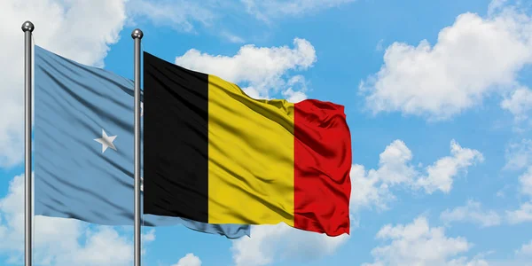 Micronesia y la bandera de Bélgica ondeando en el viento contra el cielo azul nublado blanco juntos. Concepto diplomático, relaciones internacionales . — Foto de Stock