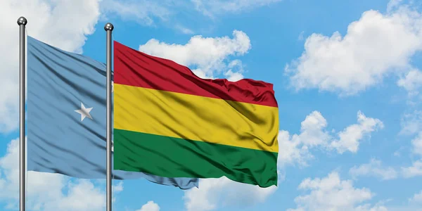 Bandera de Micronesia y Bolivia ondeando en el viento contra el cielo azul nublado blanco juntos. Concepto diplomático, relaciones internacionales . — Foto de Stock