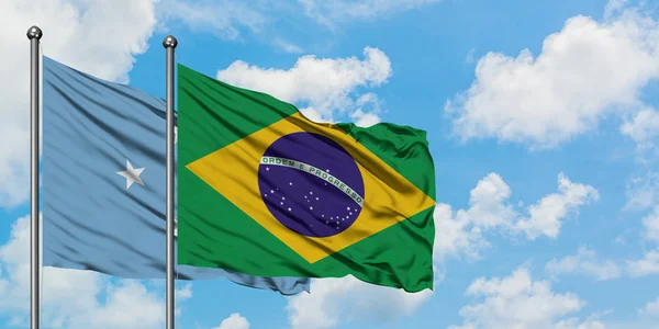 Micronesia y la bandera de Brasil ondeando en el viento contra el cielo azul nublado blanco juntos. Concepto diplomático, relaciones internacionales . — Foto de Stock