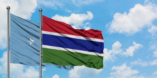 Bandera de Micronesia y Gambia ondeando en el viento contra el cielo azul nublado blanco juntos. Concepto diplomático, relaciones internacionales . — Foto de Stock