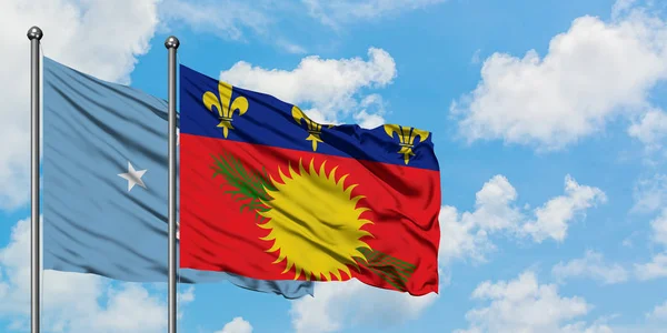 Bandera de Micronesia y Guadalupe ondeando en el viento contra el cielo azul nublado blanco juntos. Concepto diplomático, relaciones internacionales . — Foto de Stock