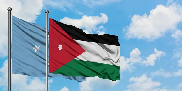 Micronesia y la bandera de Jordania ondeando en el viento contra el cielo azul nublado blanco juntos. Concepto diplomático, relaciones internacionales . — Foto de Stock
