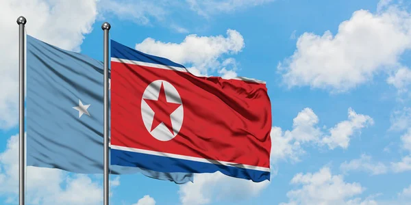 Mikronesien och Nord Korea sjunker vifta i vinden mot vit grumlig blå himmel tillsammans. Diplomatisk koncept, internationella relationer. — Stockfoto