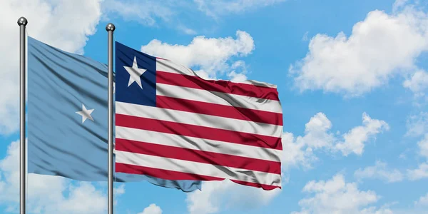 Bandera de Micronesia y Liberia ondeando en el viento contra el cielo azul nublado blanco juntos. Concepto diplomático, relaciones internacionales . —  Fotos de Stock