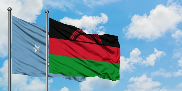 Micronesia y la bandera de Malawi ondeando en el viento contra el cielo azul nublado blanco juntos. Concepto diplomático, relaciones internacionales . — Foto de Stock