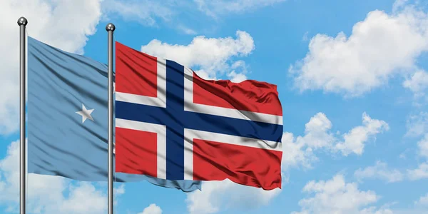 Micronesia y bandera de Noruega ondeando en el viento contra el cielo azul nublado blanco juntos. Concepto diplomático, relaciones internacionales . — Foto de Stock