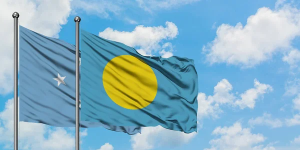 Micronesia y la bandera de Palaos ondeando en el viento contra el cielo azul nublado blanco juntos. Concepto diplomático, relaciones internacionales . — Foto de Stock