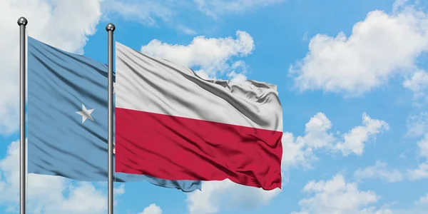 Mikronésie a polská vlajka mávali ve větru proti bíle zatažené modré obloze. Diplomacie, mezinárodní vztahy. — Stock fotografie