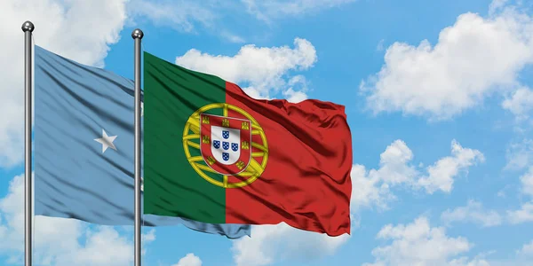 Mikronesien och Portugal sjunker vifta i vinden mot vit grumlig blå himmel tillsammans. Diplomatisk koncept, internationella relationer. — Stockfoto