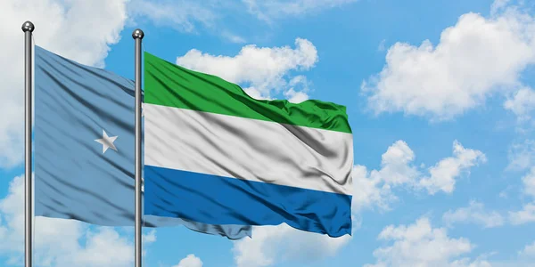 Vlajka Mikronésie a Sierry Leone mávali větrem po bílém zatažené modré obloze. Diplomacie, mezinárodní vztahy. — Stock fotografie