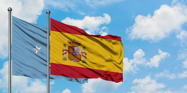 Mikronesien und Spanien schwenken gemeinsam die spanische Flagge im Wind gegen den wolkenverhangenen blauen Himmel. Diplomatie-Konzept, internationale Beziehungen. — Stockfoto